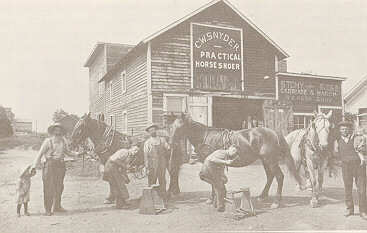 Men, children, and horses pose in front of a storefront.