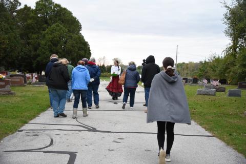 group of people being lead down a path in a cemetery